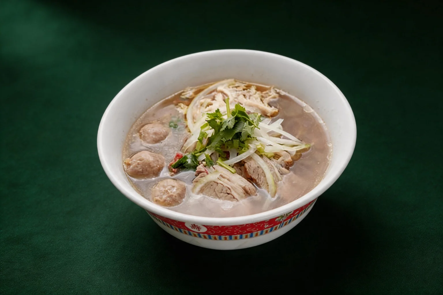 Special phở soup in a white bowl with a red border: beef balls, beef, onion and coriander, on a dark green background
