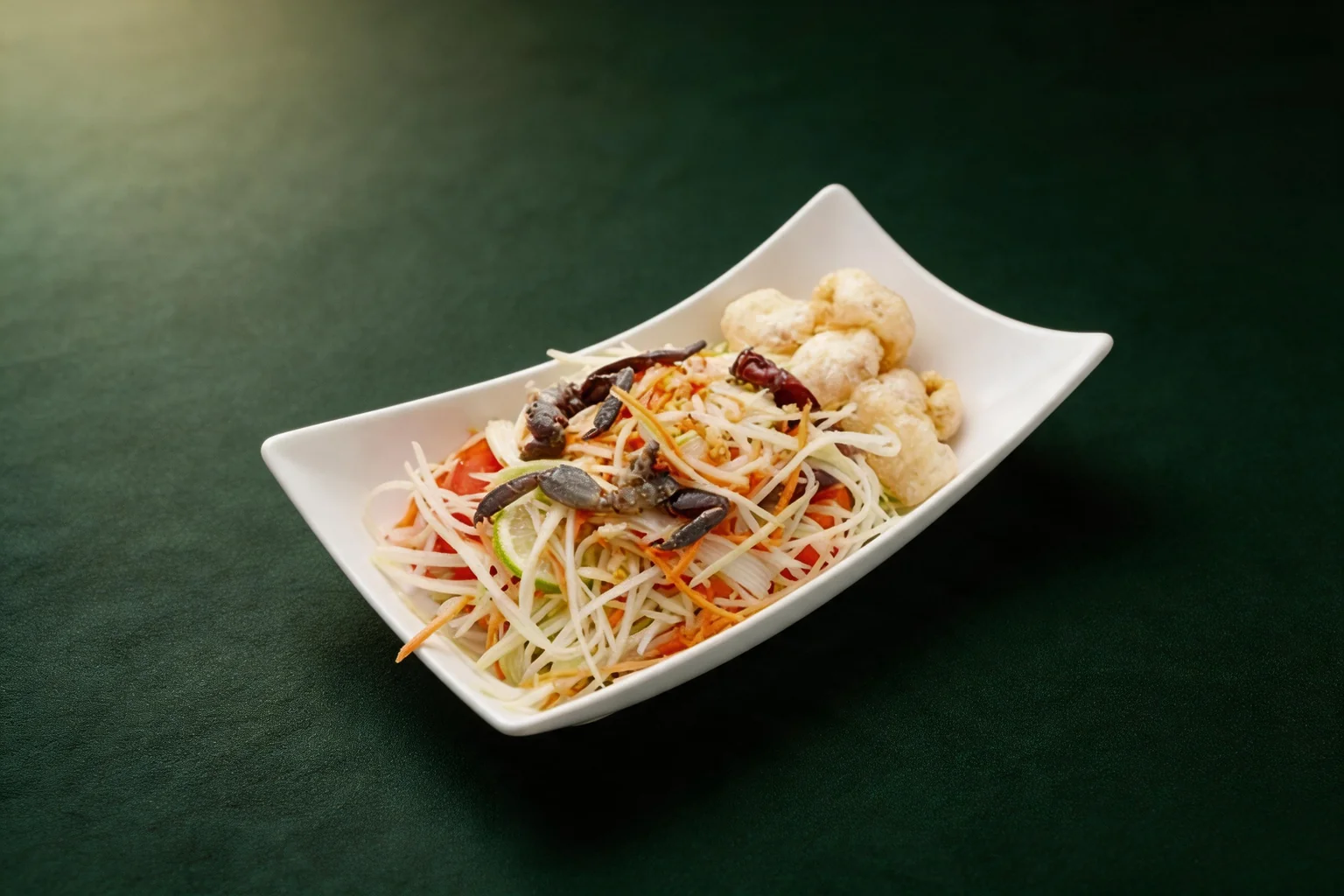 Papaya salad in a white rectangular dish, dark green background